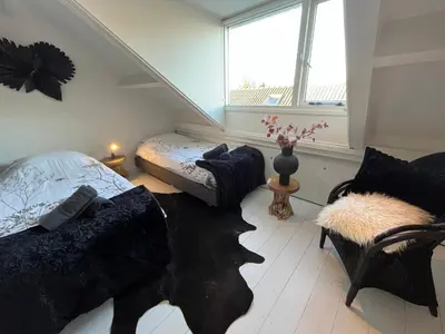 a room with two beds and a couch and a window at Guesthouse BedNboot met terras aan het water in Rijpwetering