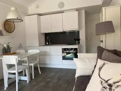 a kitchen and living room with white cabinets and a table at Shorestay Zandvoort Beachhouse in Zandvoort