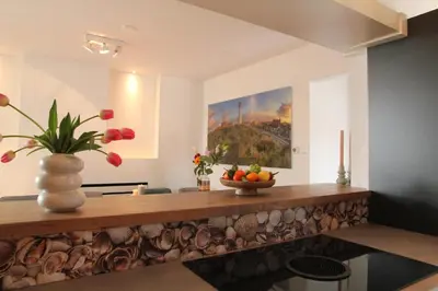 a kitchen with a counter with a vase of flowers at Vakantiehuis Tussen Duin en Strand by Droomvilla in Egmond aan den Hoef