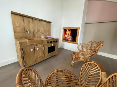 a kitchen with a stove and chairs and a fireplace at Vakantiehuis Tussen Duin en Strand by Droomvilla in Egmond aan den Hoef