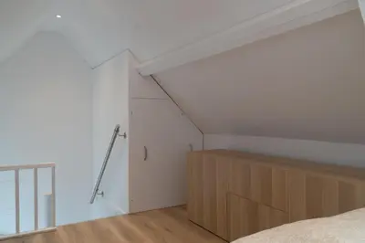 an attic bedroom with a bed and a closet at Zomerhuis aan Zee in Noordwijk aan Zee