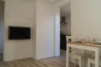 a living room with a tv on a white wall at Zomerhuis aan Zee in Noordwijk aan Zee