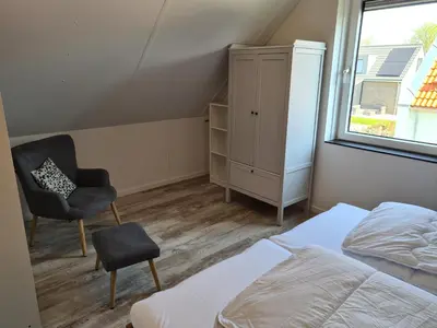 a bedroom with a bed and a chair and a window at Bungalow 69 op Recreatiepark De Wielen in Sint Maarten