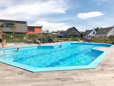 a large swimming pool with people in the water at Bungalow 69 op Recreatiepark De Wielen in Sint Maarten
