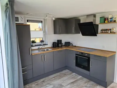 a kitchen with grey cabinets and a sink and a window at Bungalow 69 op Recreatiepark De Wielen in Sint Maarten