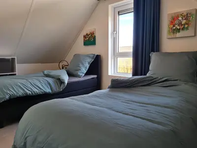 a bedroom with two beds and a window at Bungalow 76 op Recreatiepark de Wielen in Sint Maarten