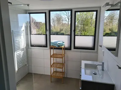 a bathroom with a sink and a towel rack and windows at Bungalow 76 op Recreatiepark de Wielen in Sint Maarten