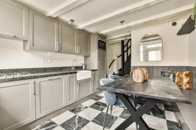a kitchen with white cabinets and a table and chairs at Spiegelgracht Apartments with Canal View in Amsterdam