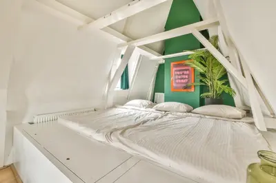 a white bed in a room with a green wall at Spiegelgracht Apartments with Canal View in Amsterdam