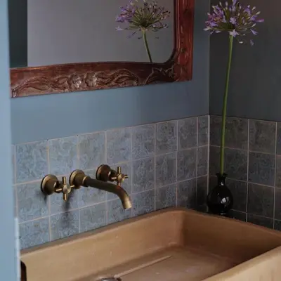 a bathroom sink with a vase with purple flowers in a mirror at Boutique B&B in Edam in Edam