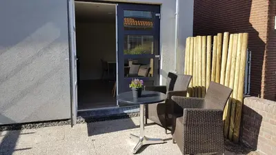 a patio with a table and chairs and a door at T-Rots, prachtig zomerhuis in Noordwijk aan Zee