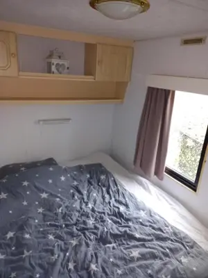 a bed in a small room with a window at De Boerenskuur..chalet.. in Assendelft