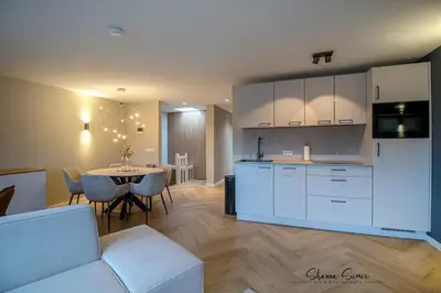 a kitchen with white cabinets and a table with chairs at ApartHotel Boutique by Urban Home Stay in Alkmaar