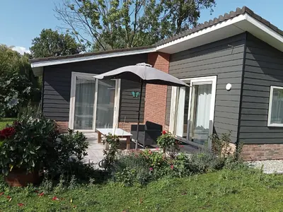 a black house with an umbrella on a patio at Domstad Resort Utrecht Vakantiewoningen in Utrecht