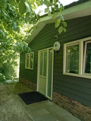 a green house with a door and a clock at Domstad Resort Utrecht Vakantiewoningen in Utrecht