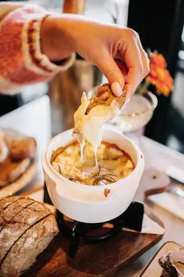 a person is dipping food into a bowl of food at Boutique Hotel LE•BAR in Zandvoort