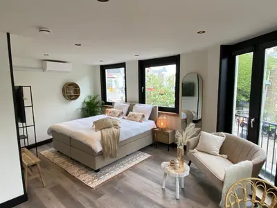 a bedroom with a bed and a couch and windows at Boutique Hotel LE•BAR in Zandvoort