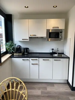 a kitchen with white cabinets and a microwave at Boutique Hotel LE•BAR in Zandvoort
