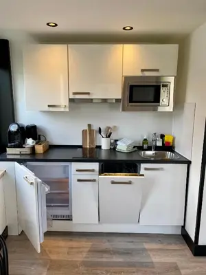 a white kitchen with a sink and a microwave at Boutique Hotel LE•BAR in Zandvoort