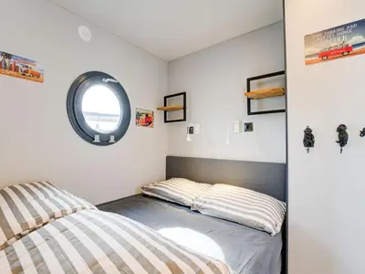 a bedroom with two beds and a round window at Beautiful houseboat in Marina of Volendam in Volendam