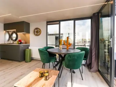 a kitchen and dining room with a table and green chairs at Beautiful houseboat in Marina of Volendam in Volendam