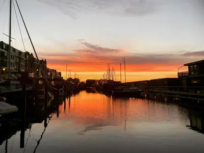 a sunset over a river with boats in it at BB aan de Zuyderzee in Bunschoten