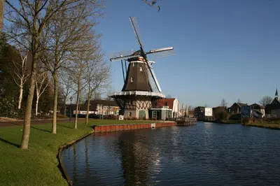 a windmill sitting on the side of a river at BB aan de Zuyderzee in Bunschoten