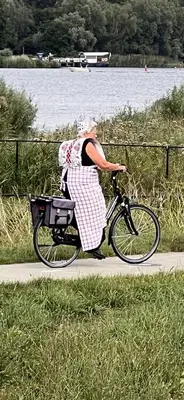a woman riding a bike down a sidewalk at BB aan de Zuyderzee in Bunschoten