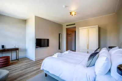 a bedroom with a white bed and a flat screen tv at Bistrotel 't Amsterdammertje in Nieuwersluis