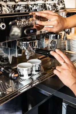 a woman making cups in a coffee shop at Bistrotel 't Amsterdammertje in Nieuwersluis