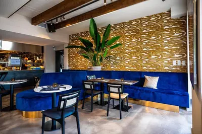 a restaurant with a blue velvet bench and tables at Bistrotel 't Amsterdammertje in Nieuwersluis