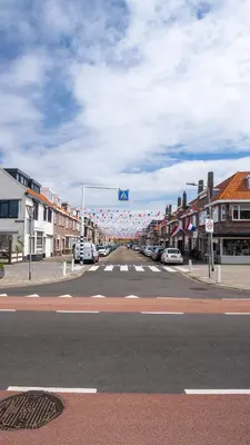 an empty city street with cars parked on the road at Shoreline Apartment Katwijk in Katwijk aan Zee