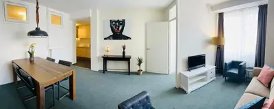 a living room with a dining table and a television at Shoreline Apartment Katwijk in Katwijk aan Zee