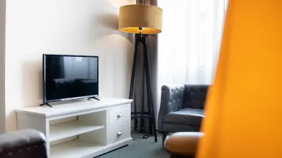 a living room with a tv and a couch and a chair at Shoreline Apartment Katwijk in Katwijk aan Zee