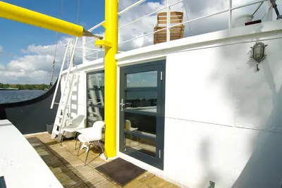 a deck of a boat with a ladder and a chair at Magnificent houseboat with a stunning view! in Amsterdam