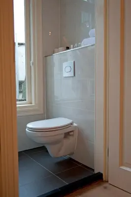 a white toilet in a bathroom with a window at Amsterdam Rembrandt Square city center Hotel in Amsterdam
