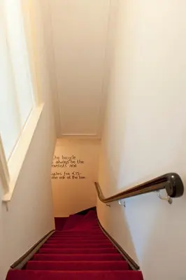 a staircase with a red carpet and a sign on the wall at Amsterdam Rembrandt Square city center Hotel in Amsterdam
