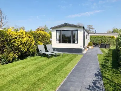 a tiny house in a garden with two chairs at Chalet 578 op Recreatiepark De Wielen in Sint Maarten