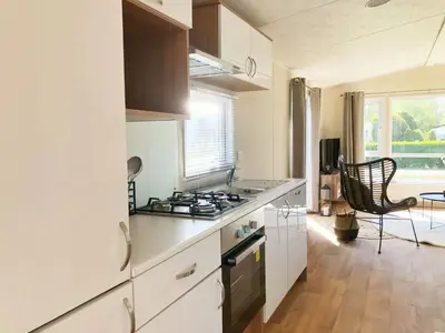 a kitchen with white cabinets and a stove top oven at Chalet 578 op Recreatiepark De Wielen in Sint Maarten