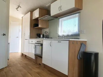 a kitchen with white appliances and wooden cabinets at Chalet 578 op Recreatiepark De Wielen in Sint Maarten