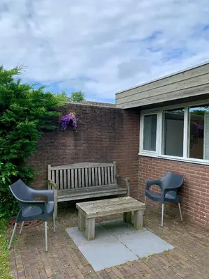 a wooden bench and two chairs next to a brick wall at Rekerlanden 79 in Warmenhuizen