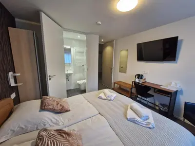 a bedroom with a bed with a desk and a television at B&B Adrina in Zeewolde