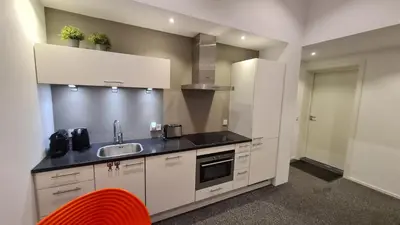 a kitchen with white cabinets and a sink and a red chair at B&B Adrina in Zeewolde
