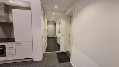 a kitchen with white cabinets and a hallway at B&B Adrina in Zeewolde