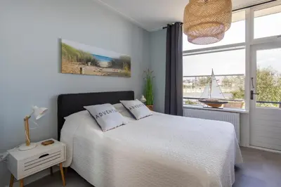 a bedroom with a bed and a window with a sailboat at Nina's Beach House 2 