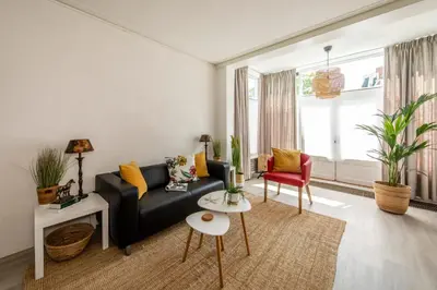 a living room with a black couch and a red chair at Nina's Beach House 2 