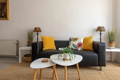 a living room with a black couch with yellow pillows at Nina's Beach House 2 