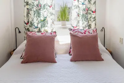 a bedroom with a bed with two pillows and a window at Nina's Beach House 1 