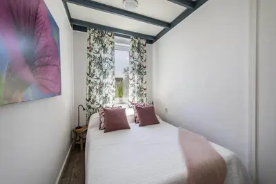 a bedroom with a bed with pink pillows and a window at Nina's Beach House 1 
