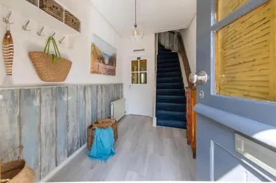a hallway with blue and white walls and a blue staircase at Nina's Beach House 1 